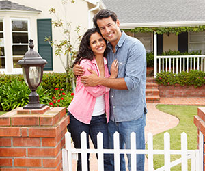 happy-couple-outside-house-84704179-SmilingToo